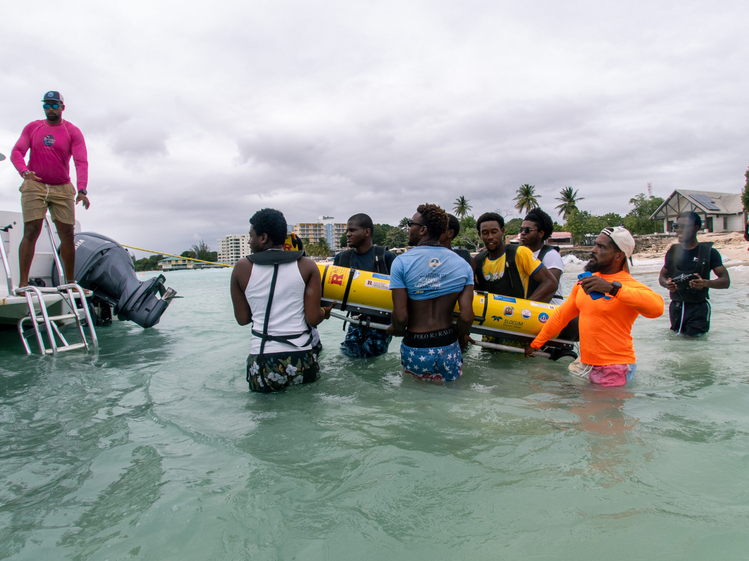 Courtney Forde (CIMH Glider Technician, orange shirt) leads a group of students carrying the glider out to the Barbados Blue dive boat for deployment (Photo by Logan Thomas, Barbados Blue).